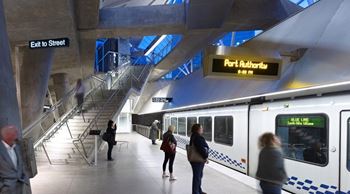 A train station with people walking and a train on the tracks.